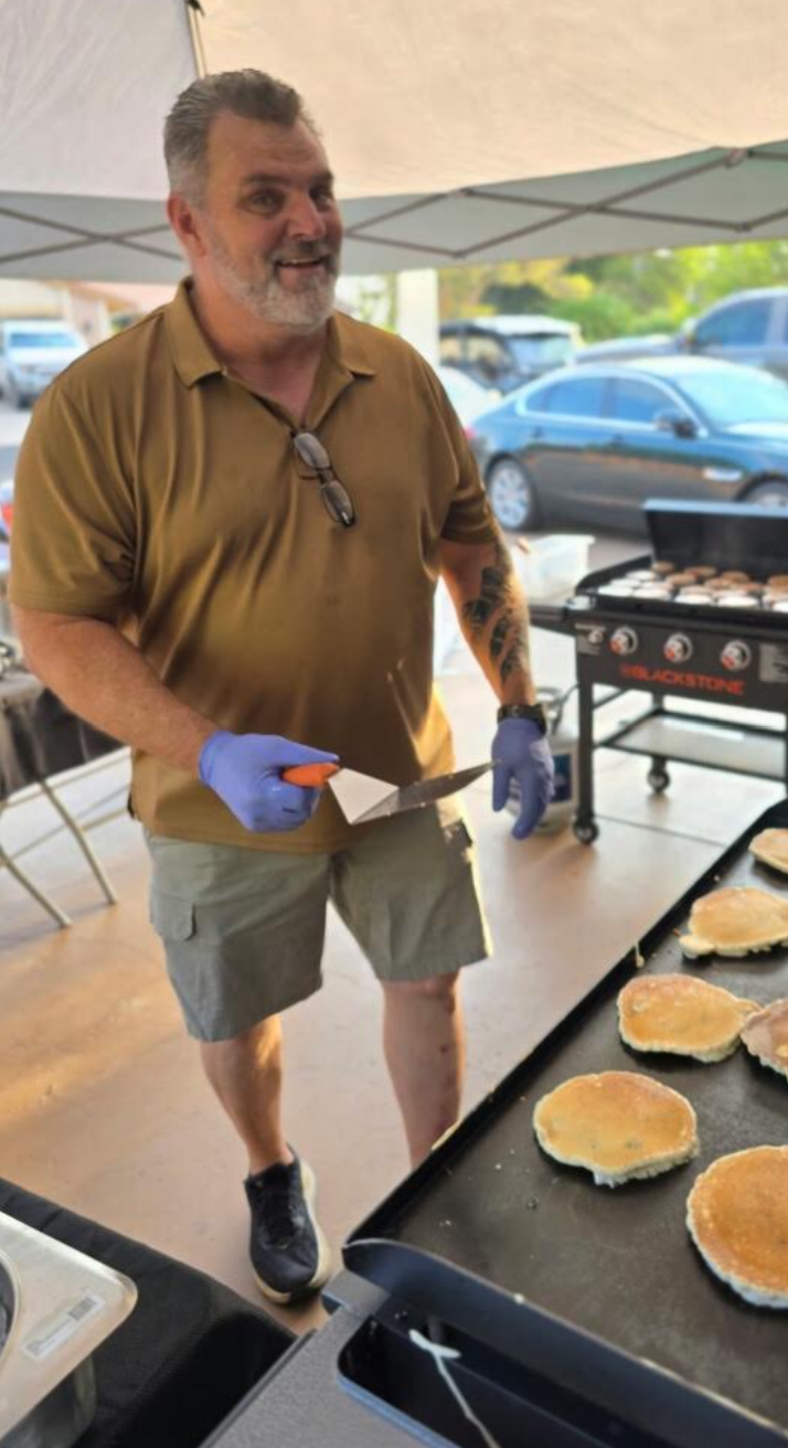 Buck Mays, founder of Pancakes & Love, cooking pancakes on a griddle at a community gathering